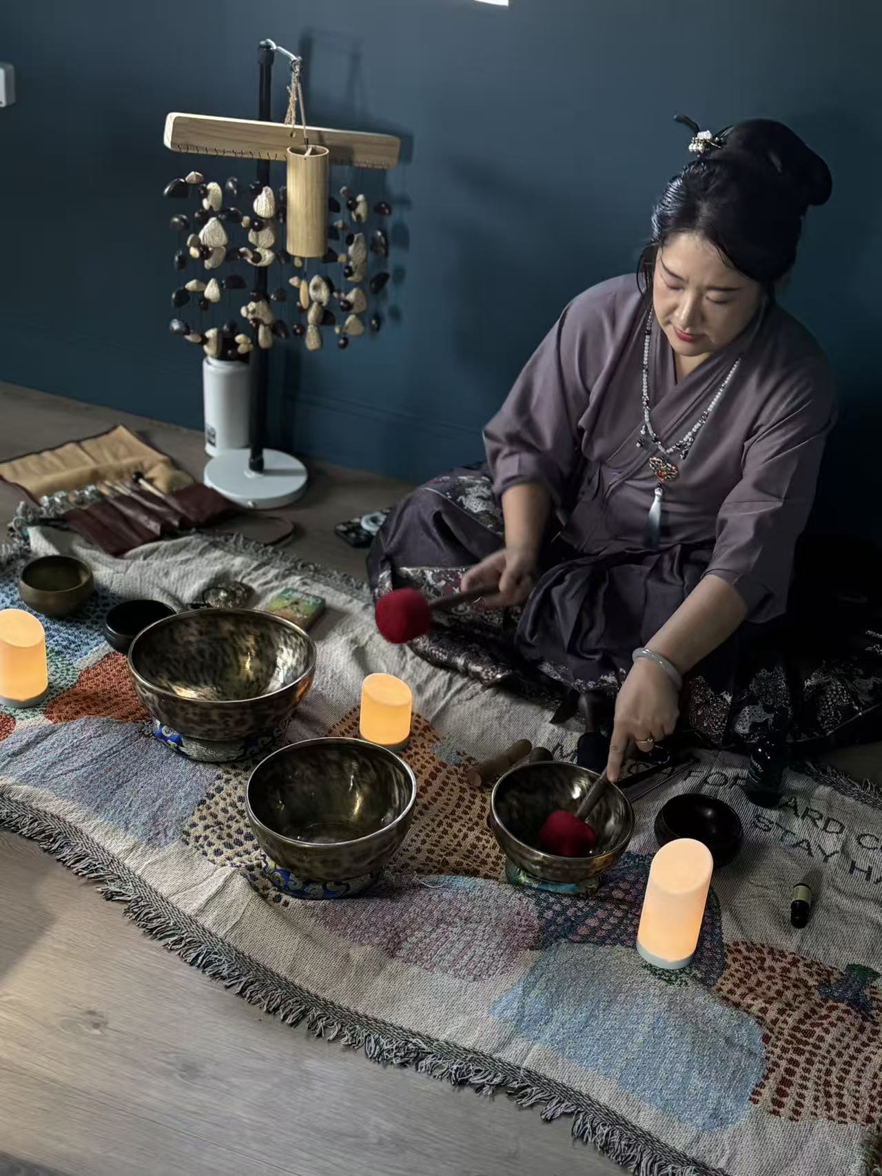 Sienna playing singing bowls with candles around the mat