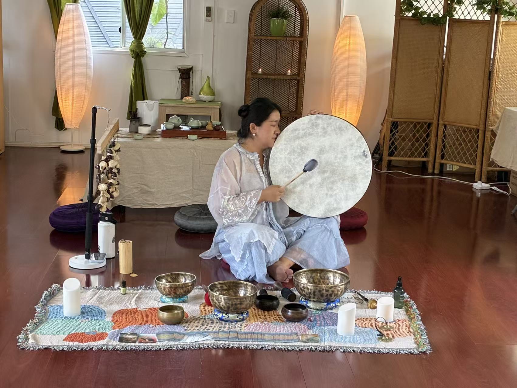 Sienna playing a frame drum during a sound healing setup