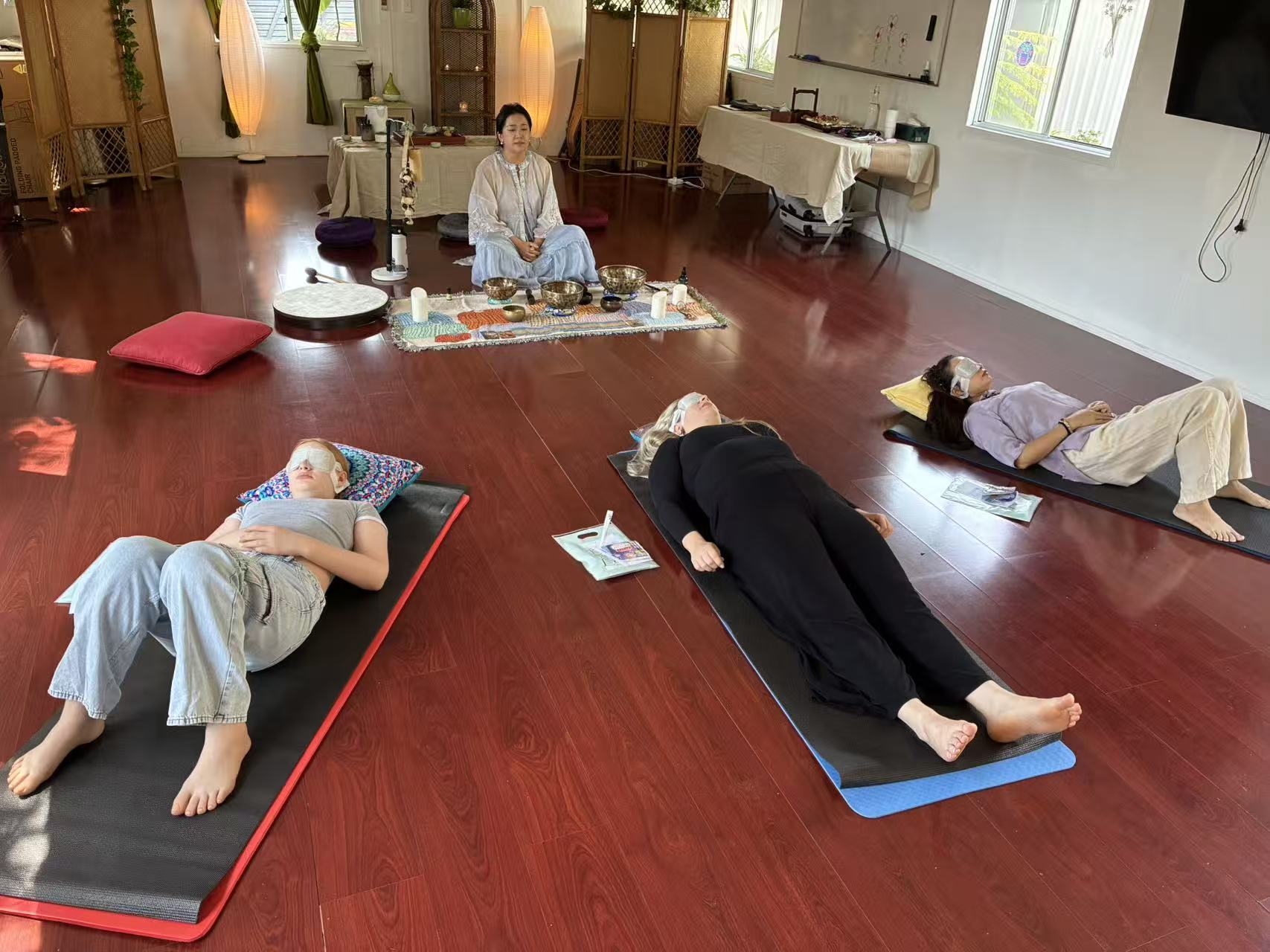 Sienna leading a sound healing event with participants resting on mats